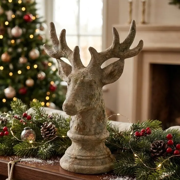 Sfeeropname van keramieken hert op sokkel tussen dennengroen, dennenappels en kerstboom