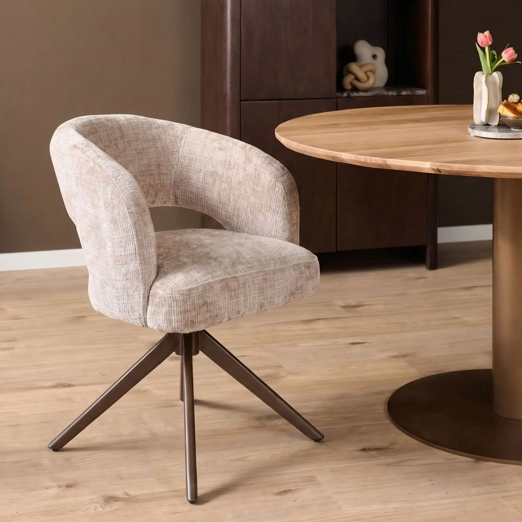 Draaibare armstoel Demi in beige stof met anodic brown metalen onderstel aan ronde eettafel