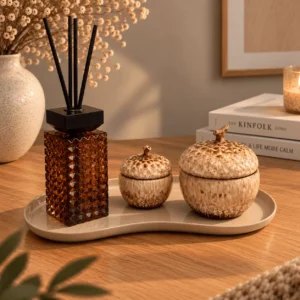 Close-up van de woonaccessoire set Herfst op een houten blad met droogbloemen, boeken 'Kinfolk Home' en 'A Life More Calm' en een brandende kaars.