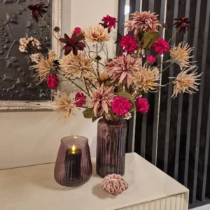 Sfeervol herfstboeket met bordeauxrode en oranje zijden bloemen in een glazen vaas